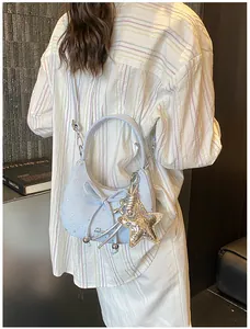 Detail van lichtblauwe tas met sterrenprint, decoratieve strik en gouden ster-hanger