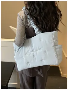 Close-up of light blue quilted tote bag with embroidered bows and ruffled shoulder strap