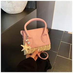 Detail of mini straw and pink leather crossbody bag with starfish pendant accessory