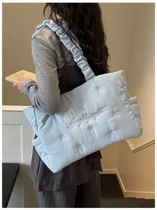 Close-up of light blue quilted nylon tote bag with ruffle straps and embroidered bows