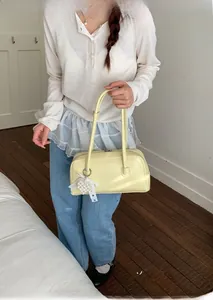 Détail du sac en cuir jaune pâle avec nœud en dentelle blanche et pendentif cœur perlé