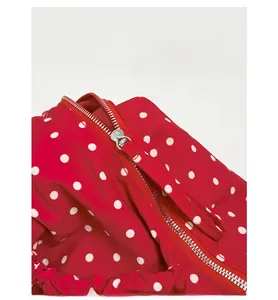 Detailed close-up of the high-quality metal zipper on a red polka dot underarm bag