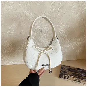 Detailopname van de witte halve maan tas met zilveren sterren en strik met metalen kralen