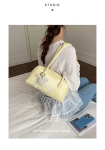 Détail d'un sac à bandoulière en cuir jaune clair avec accessoire pendentif cœur en dentelle
