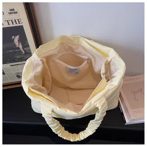 Detail view of cream quilted nylon tote bag interior with zipper pocket and cloud handle
