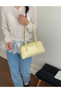 Détail d'un sac sous le bras minimaliste en cuir verni jaune clair avec fines lanières