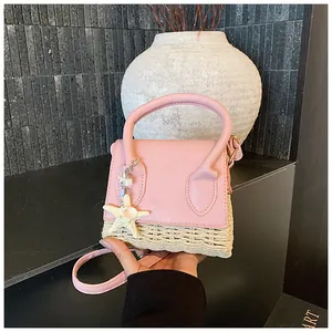 Macro detail of mini straw crossbody bag featuring pink leather and starfish charm