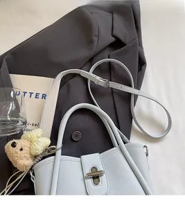 Detail of light blue bucket bag with metal buckle and cute plush bear charm decoration