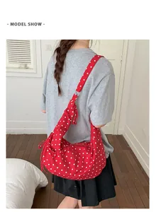 Red polka dot shoulder bag shown on model highlighting size and drape of the canvas fabric