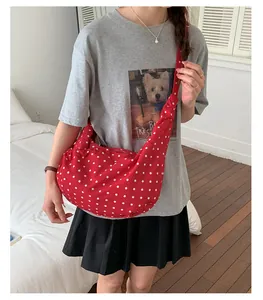 Red polka dot shoulder bag shown on model in a cozy bedroom setting for daily lifestyle use