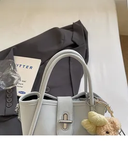 Detail of light blue lychee pattern bucket bag with bear charm on white bedding
