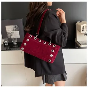 Detail shot of wine red suede baguette bag featuring punk silver metal eyelets accents