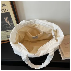 Interior detail of white nylon tote showing fabric lining and secure zipper pocket