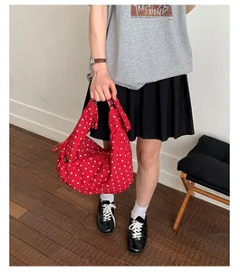 Close-up of red polka dot crescent shoulder bag featuring knotted strap and tassel detail