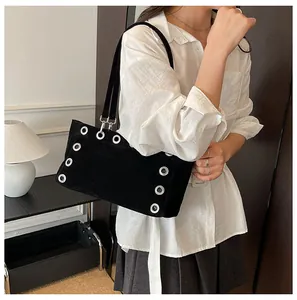 Detail of black suede baguette bag featuring oversized silver metal grommet punk accents