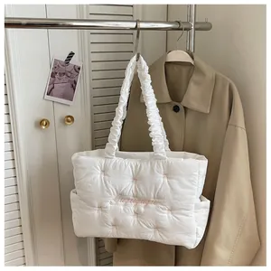 Detail of white quilted tote bag featuring pink stitching and floral cursive embroidery