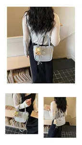 Detail view of light blue lychee pattern bucket bag with bear pendant and metal lock clasp