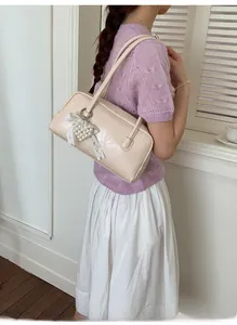 Détail du sac polochon crème avec pendentif cœur en perles et nœud en dentelle délicat