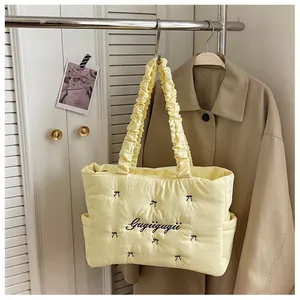 Detail of light yellow quilted tote bag featuring black bow embroidery and ruffled handles