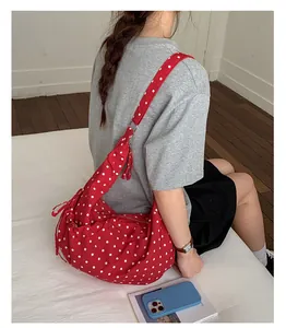Detailed view of red polka dot hobo bag with side drawstring and top metal zipper
