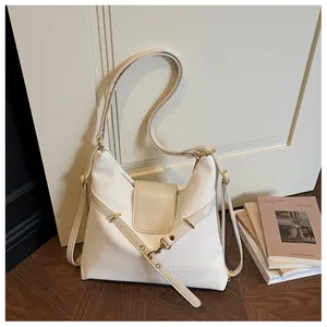 Detailweergave van crèmewitte waxlederen shopper met decoratieve bandjes en goudkleurige clips