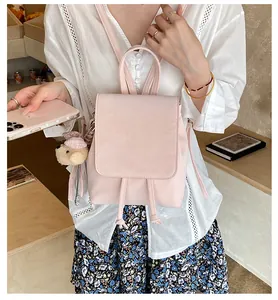 Close-up of a pink PU leather backpack with drawstring closure and cute bear pendant