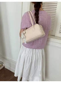 Détail du sac à main Boston beige avec breloque en perles et détails de texture cuir