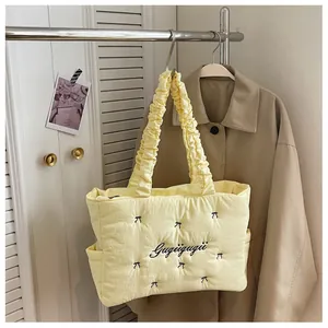 Detail of yellow quilted tote bag with black bow embroidery and ruffled shoulder strap