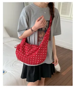 Detail of red polka dot crossbody bag with side drawstring bows and canvas texture
