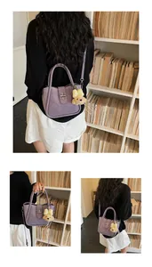Detailed view of purple lychee pattern bucket bag with bear pendant and metal lock