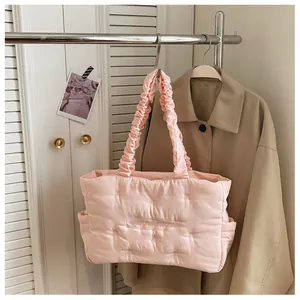 Pink quilted puffer tote bag with ruched handle and side pocket hanging on a metal rack