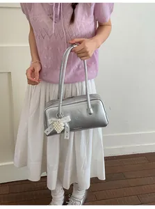 Détail du sac à main argenté métallisé avec breloque cœur perlé et nœud en dentelle