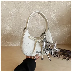 Detail van een witte hobo-tas met zilveren sterrenprint en grote sterhanger van pailletten