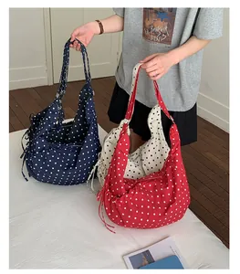 Detailed view of polka dot tote bags showing side drawstring and metal zipper closure