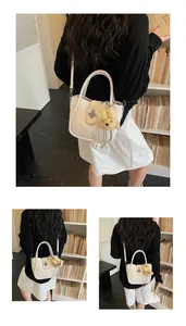 Detail of cream bucket bag with litchi texture, metal clasp and cute puppy charm