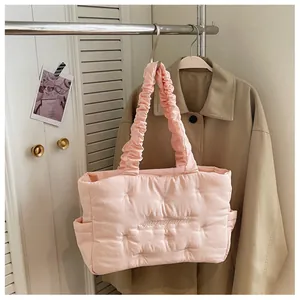 Detail of pink quilted nylon tote with ruffled straps and bow embroidery accents