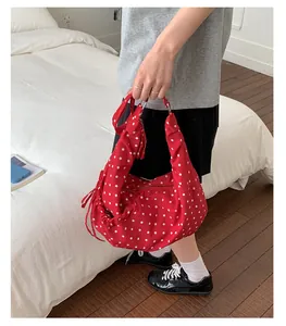 Detail of red polka dot slouchy shoulder bag with side drawstring and metal zipper
