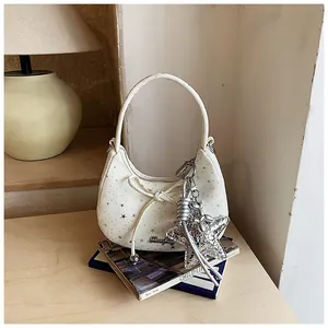 Detailopname van de witte halvemaantas met zilveren sterbedeltjes en een strikdetail