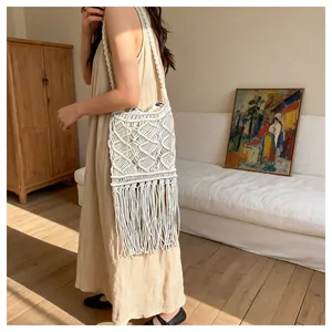 Detailed macro view of white macrame weaving pattern and long tassel fringes on beach bag