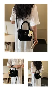Close-up of black lychee texture bucket bag with metal lock and bear charm accessory