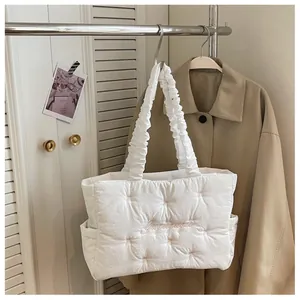 Detail of white quilted nylon tote with pink embroidery and pleated shoulder straps