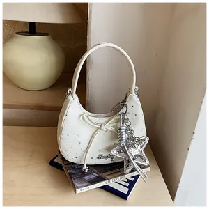 Detail van witte hobo-tas met zilveren sterrenprints en een grote sterrenhanger