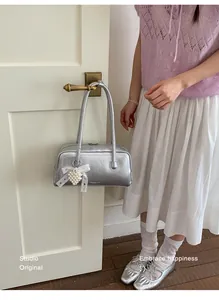 Détail du sac oreiller argenté avec nœud en dentelle, pendentif perle et ballerines