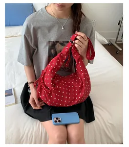 Polka dot red dumpling bag with bow side details and wide shoulder strap style
