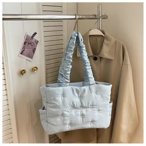 Detail of light blue quilted nylon tote bag featuring cloud handle and side pocket