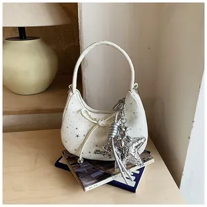 Detail van witte maantas met zilveren sterren, strik en Y2K-sterhanger decoratie