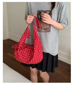 Detailed close-up of a red polka dot hobo bag with drawstring and zipper closure