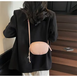 Detail of light pink lychee leather crossbody bag on a black blazer for a high-contrast look