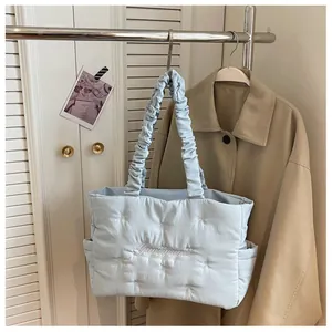 Detail of light blue quilted tote bag with embroidery and ruffle shoulder strap