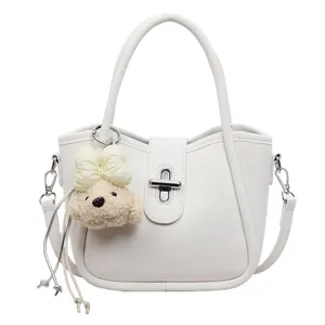 Detail of cream white bucket bag featuring silver twist lock and cute bear charm